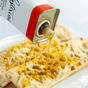 A tin of Kosterina Spicy Red Pepper Olive Oil is being poured over slices of crusty bread on a white surface.