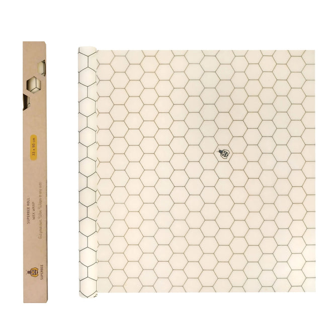 The SuperBee Beeswax Wrap Roll, featuring a white honeycomb hexagon grid with a small bee illustration, sits beside a rectangular brown box with a hexagon window and yellow label—ideal for reusable food storage.
