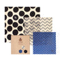 The SuperBee Beeswax Wrap Beeginner Set features three reusable food wraps in black polka dots, grey zigzag, and white polka dots on blue, displayed next to a brown SuperBee box for eco-friendly food storage.