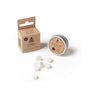 A small cardboard box and round metal tin, both labeled SuperBee Dentos Eco Toothpaste Tabs, Spearmint Flavor, with white hexagonal vegan tabs scattered in front—travel-friendly toothpaste displayed on a white background.