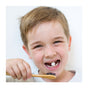 A smiling young boy with light brown hair, holding a bamboo toothbrush, shows his missing tooth and gets ready to try SuperBee's Dentos Eco Toothpaste Tabs in Spearmint flavor, standing against a plain white background.