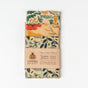 SuperBee Essentials Beeswax Wraps, a set of 3 reusable wraps with floral designs, are packaged together and wrapped with a brown label showing sizes and details about their eco-friendly, plastic-free food storage materials.