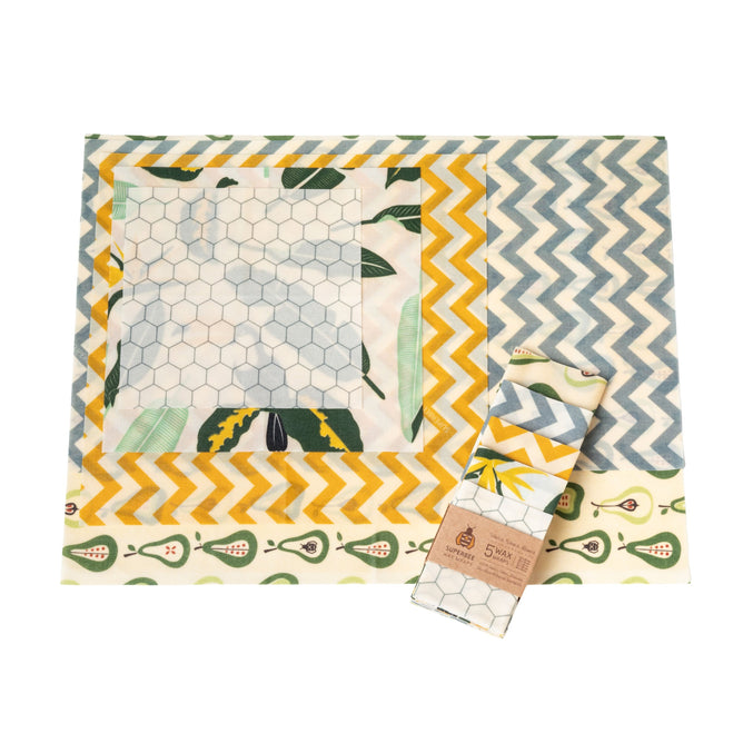 SuperBee Essentials Beeswax Wraps, 5 Wax Wraps in assorted sizes and patterns—hexagons, yellow chevrons, blue zigzags, and botanicals—shown flat with one folded in packaging for plastic-free food storage.