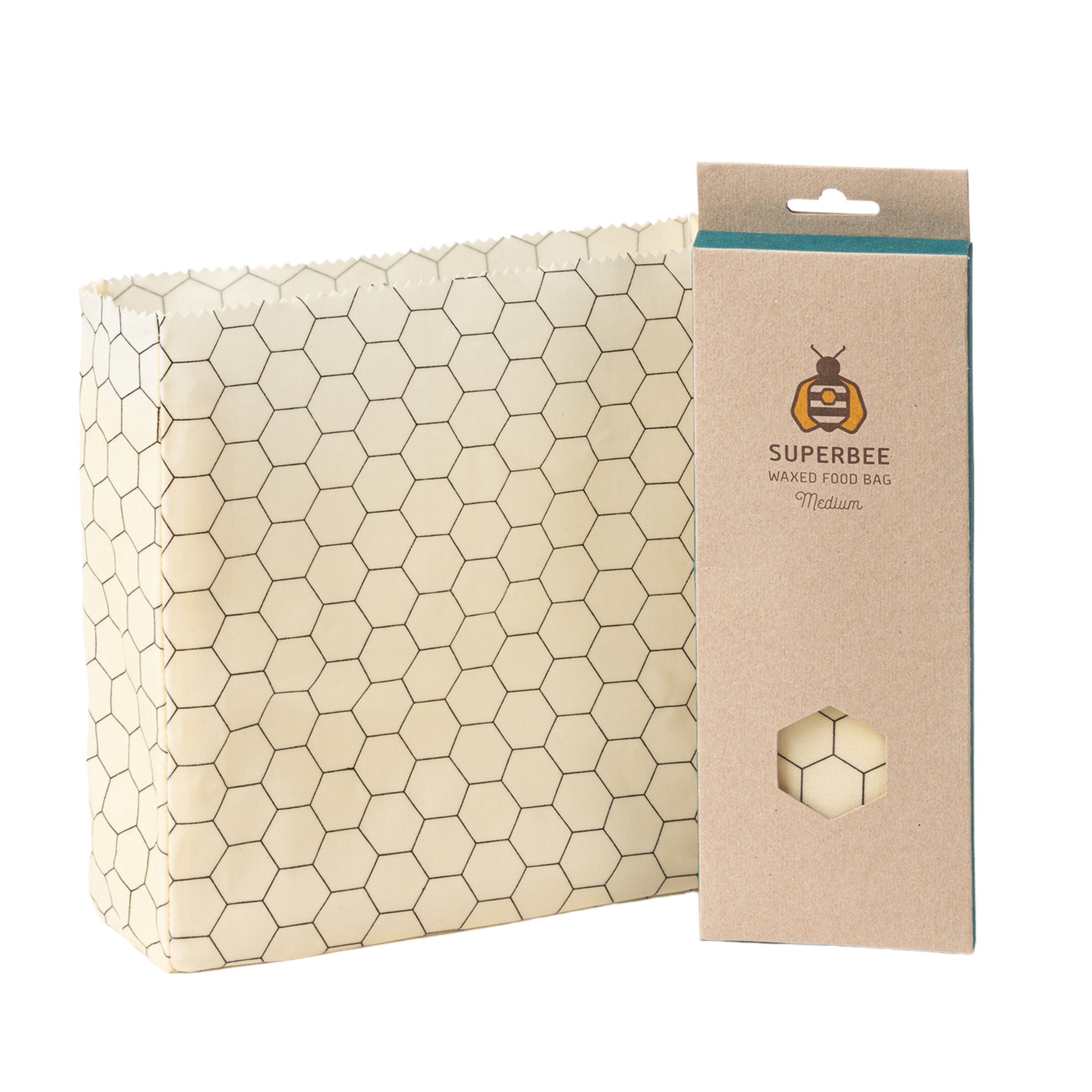 SuperBee’s Waxed Food Bag, a rectangular reusable bag with a honeycomb pattern, is shown beside its brown packaging featuring a bee logo and hexagon window that reveals the waxed food storage bag inside.