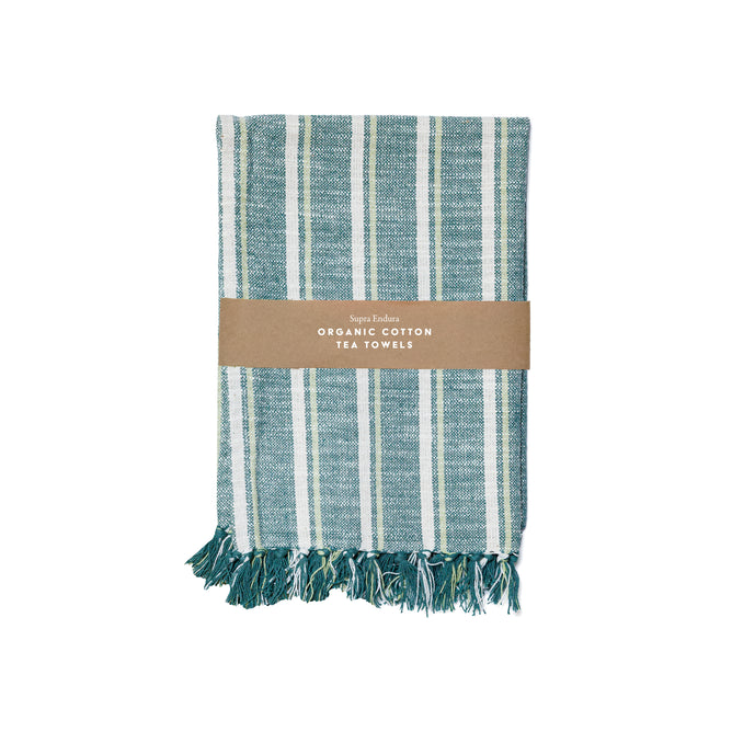 A folded teal and white Striped Organic Cotton Tea Towel Set by Supra Endura with fringe, wrapped in a brown paper label reading "Organic Cotton Tea Towels.