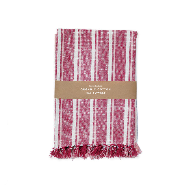 A folded red and white striped organic cotton tea towel with fringed edges, wrapped in a brown paper band labeled Supra Endura Striped Organic Cotton Tea Towel Set.