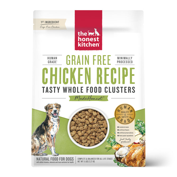 A bag of The Honest Kitchen Dry Dog Food, Grain Free Chicken Whole Food Clusters, with dog, chicken, and veggie illustrations. Labels show its human grade, grain free, and minimally processed.