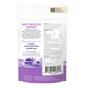The back of The Honest Kitchen Instant Goat's Milk Plus package lists ingredients, nutrition facts, and feeding tips, spotlighting probiotics for dogs and cats. The design has purple accents and a small farm landscape illustration at the bottom.