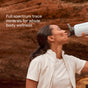 A woman outdoors drinks from a reusable water bottle near red rocks. Text reads: “Trace Minerals ConcenTrace Daily Mineral Powder—full spectrum trace minerals and daily supplement for whole body wellness.”.