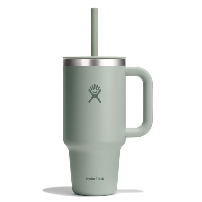A 32 oz Travel Tumbler from Hydro Flask in sage green, featuring a right-hand handle, lid with straw, simple wave logo near the top, and leak-resistant insulation.