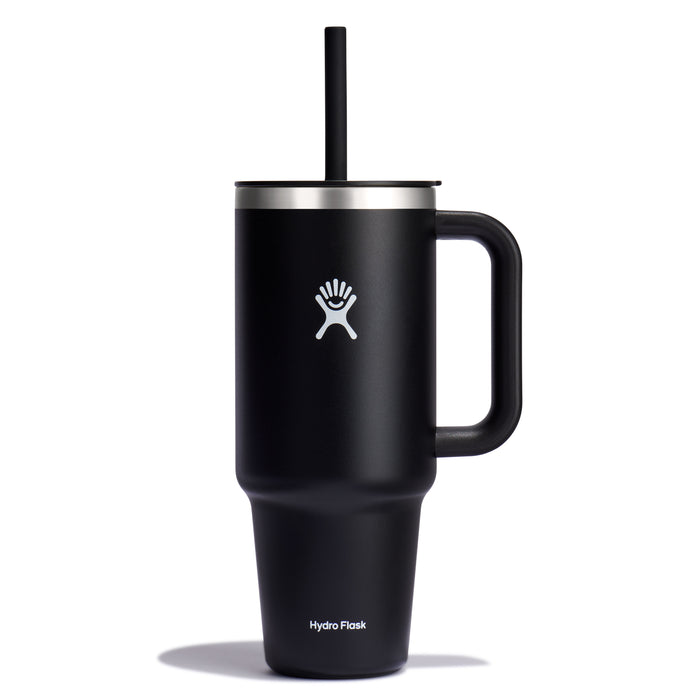 The black Hydro Flask Travel Tumbler, 40 oz, with a large handle and straw lid, showcases double-wall vacuum insulation for temperature control. Its design features the logo and a stylized figure with outstretched arms at the base.