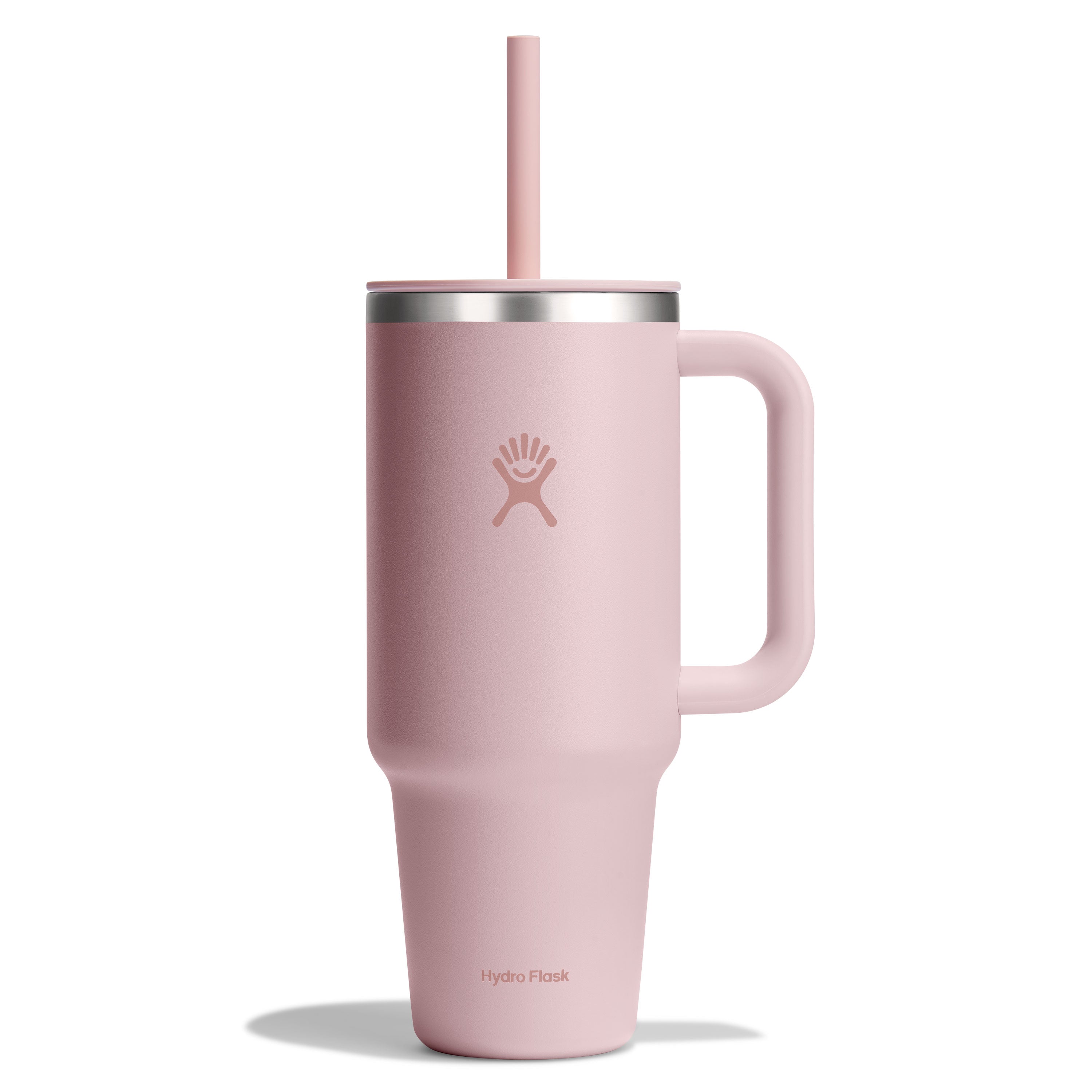 The Hydro Flask Travel Tumbler, 40 oz, is tall, powder pink with a handle and straw. It features double-wall vacuum insulation, a leak-resistant lid, silver rim, and the brand logo on its side.