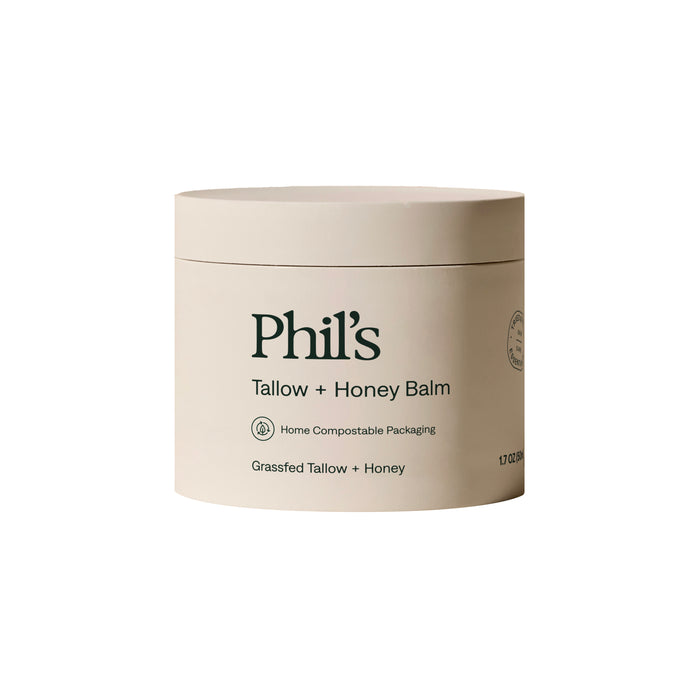 Phil’s Tallow + Honey Balm, in a beige home compostable container with a minimal design, sits on a white background. This multipurpose balm features nourishing grassfed tallow and honey as key ingredients.
