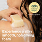 A person with wet hair uses ATTITUDE super leaves Body Soap Bar on their shoulder. Text reads: +99% natural origin¹ and experience a silky smooth, non-drying foam. Small text cites ISO 16128.
