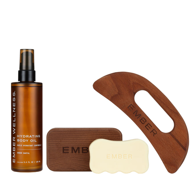 The Body Sculpting Set by Ember Wellness features a hydrating body oil, two EMBER-labeled body serum bars, and two wooden massage tools—an ideal kit for body sculpting, beautifully arranged on a white background.