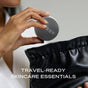 A person puts a round silver Ember Wellness container labeled The Complete Minibar Set into a black pouch. Text reads: TRAVEL-READY SKINCARE ESSENTIALS—perfect for storing your solid moisturizing or highlighting bars on the go.