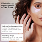 A woman with curly hair wears The Good Patch Brighten-Up Hydrogel Undereye Patch. Text reads: Clinically proven after 1 use. Targets dark circles, boosts under-eye brightness, and smooths fine lines with a teardrop shape for precise fit.