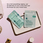 Two Un-Frown Wrinkle Microdart Patch packets from The Good Patch rest on a white tray with a pink backdrop. Text highlights their use for smoothing crow’s feet and frown lines; spa items add to the relaxing scene.