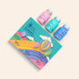 Soar to New Heights by The Powder Shampoo is a travel set featuring three pastel powder shampoos (pink, blue, turquoise) in a vibrant Cappadocia hot air balloon–inspired box, labeled “Life is like a shampoo.”.