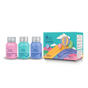 Three colorful bottles of The Powder Shampoo and Foam Wash stand beside the Soar to New Heights travel set box, featuring Cappadocia hot air balloons and a rainbow on a pastel sky. Pink, blue, and teal bottles have silver caps.