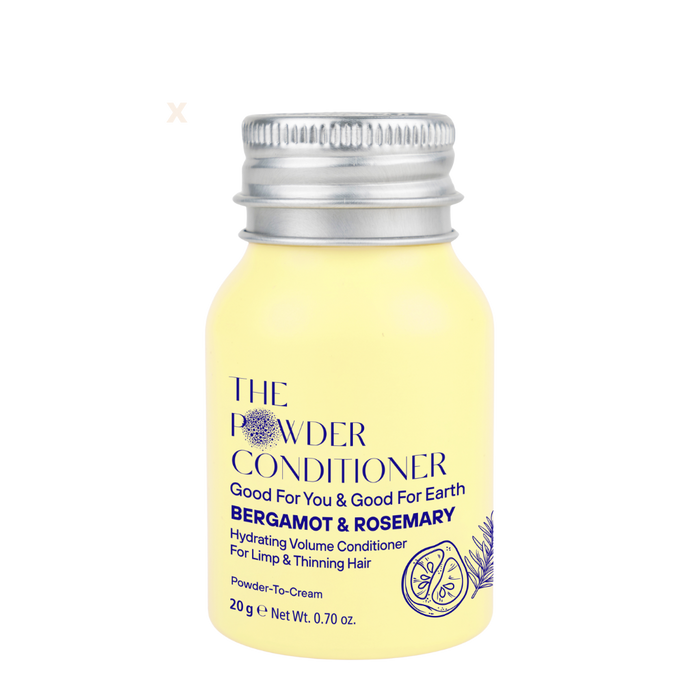 A small yellow bottle labeled Hydrating Volume Conditioner by The Powder Shampoo, with bergamot and rosemary for fine and thinning hair. Features a metal screw cap and delicate botanical illustrations.