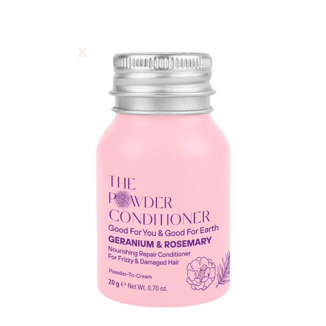 A small pink bottle of The Powder Shampoo’s Nourishing Repair Conditioner with geranium, rosemary, and natural oils for frizzy and damaged hair, featuring a silver cap and purple text on the front.