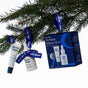The Winter Hydration Gift Set featuring a gift box, a lip treatment tube, and a serum bottle with blue ribbons hanging from a pine branch.