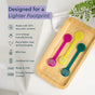 Three colorful Radius Tongue Cleaner & Storage Case sets in yellow, green, and pink are displayed on a wooden tray beside a list of eco-friendly features—including recycled content, low-energy manufacturing, and BPA-free materials—making them an ideal addition to any oral care routine.