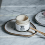 Anima Mundi's TOOTH POLISH, Fluoride Free, is displayed open in a glass jar on a ceramic dish beside a bamboo toothbrush with white bristles—all atop marble—a chic, plant-based oral care solution.