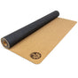 A partially rolled Nomad Air Cork Yoga Mat by Yoloha Yoga, featuring an eco-friendly cork surface, a black underside, and a small circular floral logo printed on one corner.