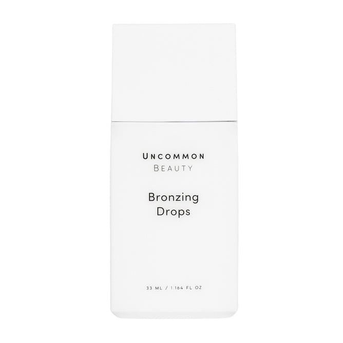 A minimalist rectangular white bottle labeled Uncommon Beauty Bronzing Drops in black text holds 33 mL (1.16 fl oz), delivering a sunkissed, post-vacation glow.