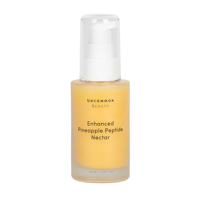 A clear bottle with a white pump dispenser holds Uncommon Beauty Enhanced Pineapple Peptide Nectar, a yellow serum, 40 mL / 1.35 fl oz.