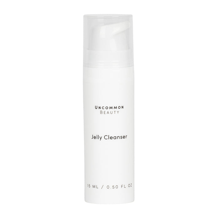A white cylindrical bottle labeled Mini Jelly Cleanser by Uncommon Beauty, with a clear cap and minimalist black text. This gentle, fragrance-free daily face cleanser contains 15 ml (0.5 fl oz) and has a plain background.