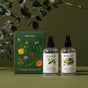 Two spray bottles from Koala Eco’s Aromatherapy Duo are shown next to a green, botanically illustrated box. Eucalyptus branches and fragrant botanicals appear blurred in the background.