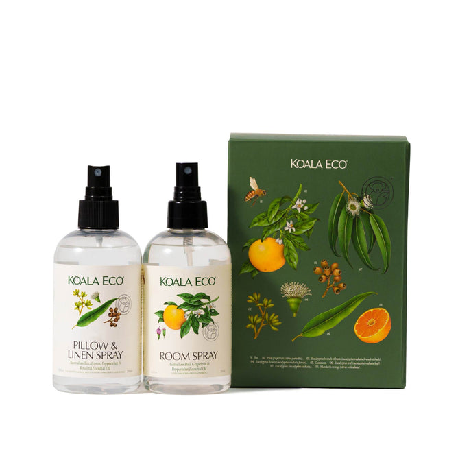 Two clear spray bottles from Koala Eco’s Aromatherapy Duo, infused with botanicals, stand beside a green gift box adorned with botanical illustrations and citrus fruits.