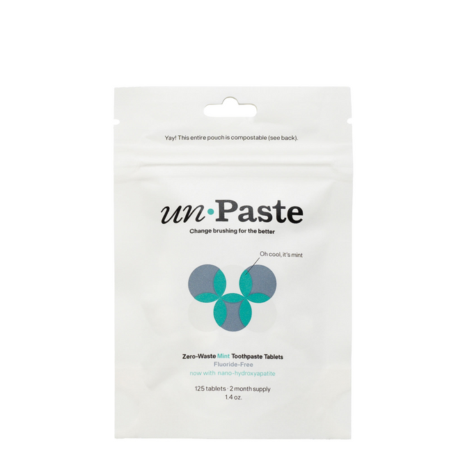 A resealable white pouch of Unpaste Fluoride Free Mint Toothpaste Tablets, with minimalist green-blue graphics. The compostable package contains 125 plastic-free tablets.