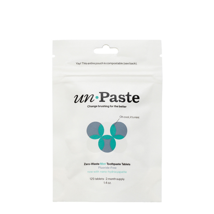 A resealable white pouch of Unpaste Fluoride Free Mint Toothpaste Tablets, with minimalist green-blue graphics. The compostable package contains 125 plastic-free tablets.