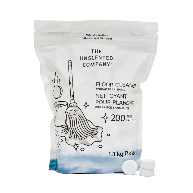 A white bag of The Unscented Company Floor Cleaning Tabs - Unscented, with a mop and bucket drawing, contains 200 streak-free tablets (1.1 kg) for deep floor cleaning. Two unscented tabs are shown in front of the eco-friendly package.