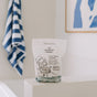A package of The Unscented Company Toilet Bowl Cleaning Tabs - Unscented rests on a white bathroom surface, accompanied by a blue and white striped towel and abstract wall art in the background.