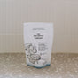 A white pouch of The Unscented Company Toilet Bowl Cleaning Tabs rests on a speckled countertop, featuring minimalist toilet and bubble illustrations and English/French text—ideal for sustainable hygiene.