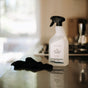 A bottle of The Unscented Company All Purpose Cleaner - Unscented sits on a kitchen counter beside a dark cleaning cloth, with a stove and soft natural light in the background; its vegan, biobased formula is eco-friendly.