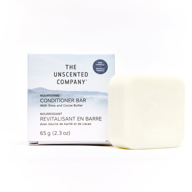 A plastic-free, unscented Conditioner Bar by The Unscented Company sits in front of its white and light blue box labeled "Nourishing Conditioner Bar with Shea and Cocoa Butter, 65g (2.3oz).
