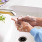 A person uses Grove Co. Hand Soap Sheets (40 Washes) (VIP) under a faucet in a white sink, creating lather. Green herbs and a purple towel are nearby.