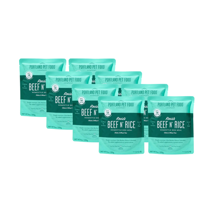 Six teal pouches of Portland Pet Food Company’s Rosies Beef N Rice Human-Grade Dog Meal (9 oz each) are arranged in a staggered row, each clearly displaying the product name and details. Great as a mixer or meal topper.