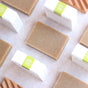 Little Seed Farm’s Matcha & Argan Bar and other rectangular beige soaps are neatly arranged with soap boxes featuring white and green labels, creating a clean, minimal look on a light surface.