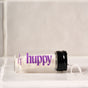A small glass jar labeled "Huppy Dental Floss, Vegan Mint - Refill" in purple text lies on its side with a black cap. Vegan floss extends from the jar, set against a light tiled surface.