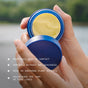 Outdoors, someone holds an open blue jar containing rich yellow cream. Text on the image highlights the product’s benefits: deep hydration, lightweight nourishment, soothing plant actives, and reducing the appearance of fine lines. The scene features Ursa Major’s Golden Hour Recovery Cream—a natural face cream crafted to revive and refresh your skin.