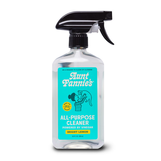 A spray bottle of Aunt Fannies Cleaning Vinegar For Cats features a blue label with a woman and child, and text noting plant-based cleaners powered by vinegar and essential oils.