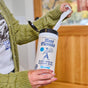 Someone pulls a Glass + Window Cleaning Wipe from an Aunt Fannie's container in a home near a wooden door.