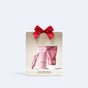 The VOESH Hand & Body Glow Set features three pink skincare tubes in a gold and white accented box with English and French descriptions, topped with a red bow for glowing skin.